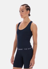 Tengerészkék sportos egyrészes, kerek nyakkivágással és széles pántokkal, hozzáillő rövidnadrággal párosítva. Logós derékrésszel, fehér felirattal.