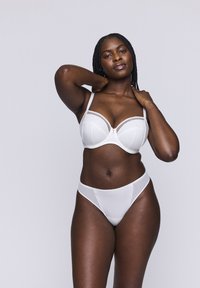 Conjunto de lencería blanca que incluye un sujetador con relleno y detalles de encaje, y una braguita transparente a juego. Textura de tela lisa, soporte con varillas y tirantes ajustables.