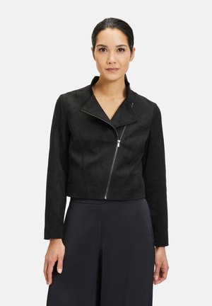 Zwarte kortere suède jas met een ingesneden kraag, asymmetrische ritssluiting en lange mouwen. Glad textuur met minimale stikdetails.
