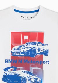 T-shirt blanc avec des graphiques bleus et rouges de deux voitures de course BMW, avec le texte "BMW M Motorsport" affiché en évidence.