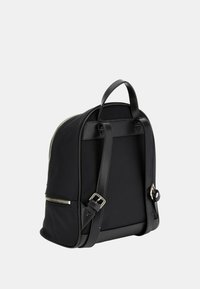 Zaino in pelle nera con forma arrotondata, dettagli in cerniera argentata, spallacci regolabili e maniglia superiore. Texture liscia con design minimalista.