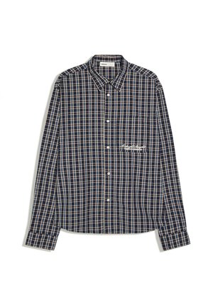 Chemise à manches longues boutonnée avec un motif à carreaux bleu marine, beige et blanc et une petite poche poitrine avec broderie de texte blanc.