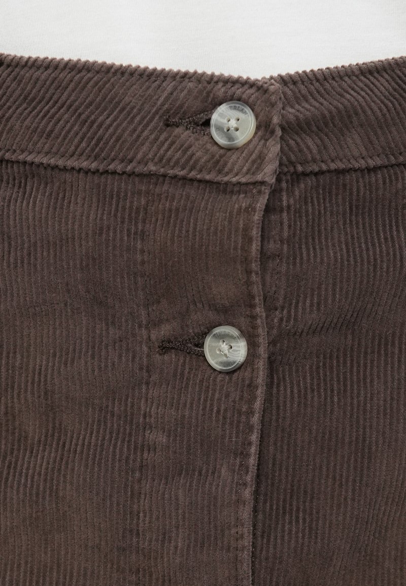 Primo piano di tessuto a coste marrone scuro con due bottoni grigi fissati su una cintura o apertura di un indumento.