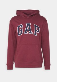 Bordowa bluza z kapturem z przednią kieszenią kangurka, regulowanym troczkiem w kapturze oraz logo "GAP" w białym i granatowym kolorze na piersi. Materiał z bawełnianej mieszanki.