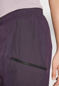 Lilla sportshorts lavet af letvægtsstof har et elastisk taljebånd og en lynlåslomme i siden med sort hardware.
