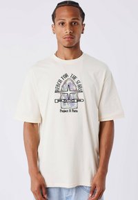 Crème-kleurig katoen T-shirt met korte mouwen, met een grafische print "REACH FOR THE STARS" en logo-ontwerp in het midden.