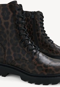 Brown leopard print ankle boots made of shiny leather, featuring black laces, a side zipper, and a textured, chunky black sole.