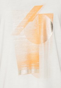 Bílé tričko s abstraktním designem obsahujícími oranžové a metalické stříbrné geometrické tvary, včetně čar a kruhů, na přední straně.