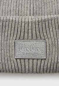 Harmaa ribbed-neulepipo, jossa on käännetty reunus ja etuosassa keskellä ommeltu suorakulmainen patch, jossa lukee "lala BERLIN".