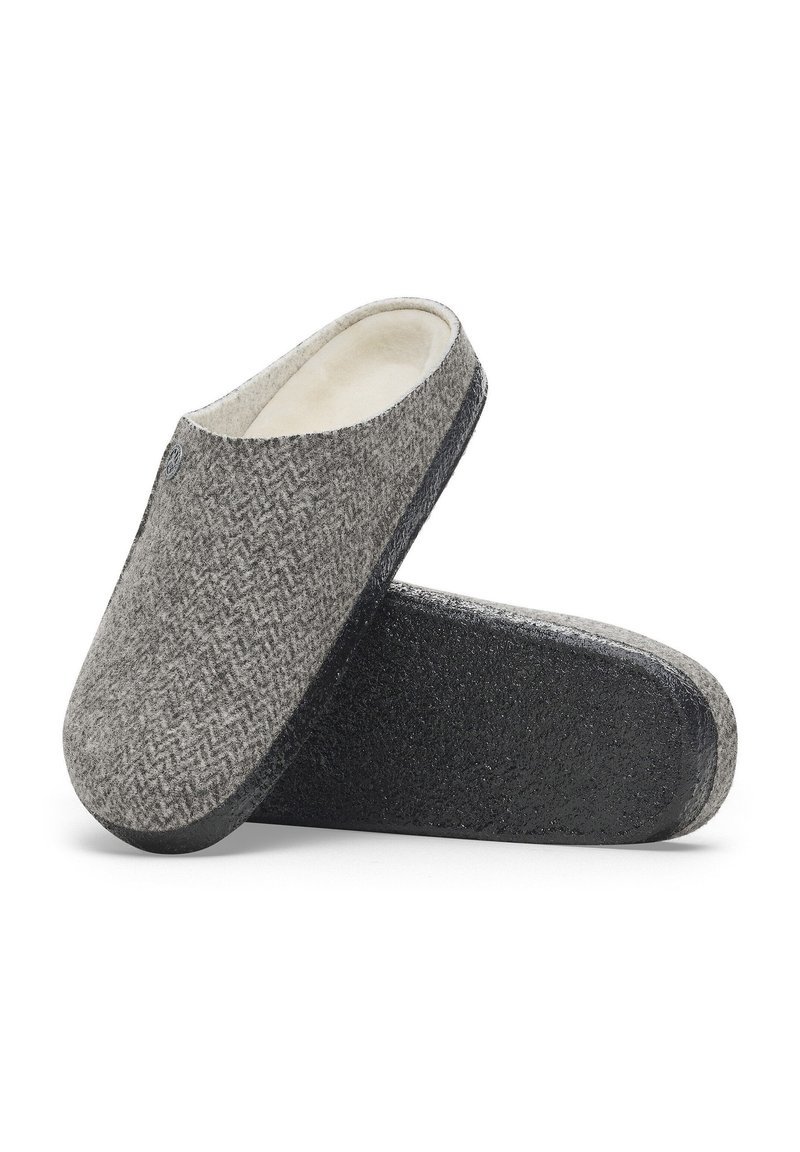 Chaussons en laine gris à motif chevrons avec une doublure beige douce et une semelle en caoutchouc noir, conçus avec un bout rond et un dos ouvert.