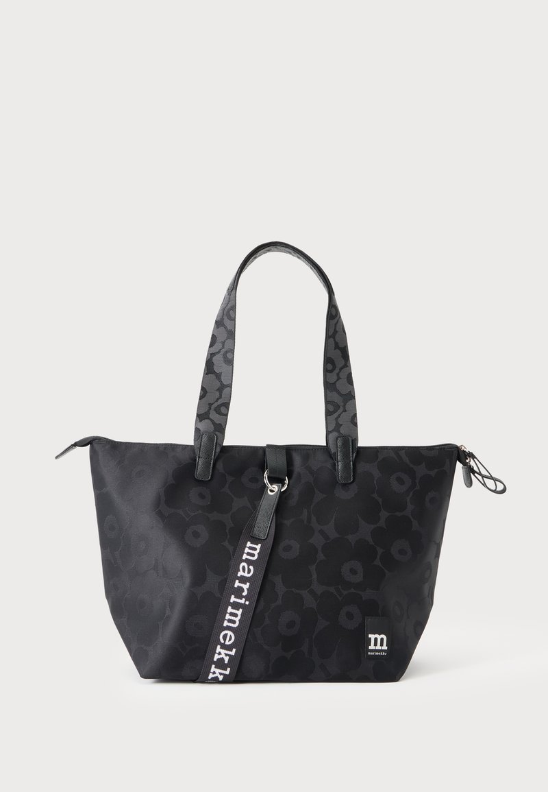 Sac cabas noir avec un motif floral subtil, double bandoulière et une étiquette frontale indiquant "marimekko" en lettres blanches.