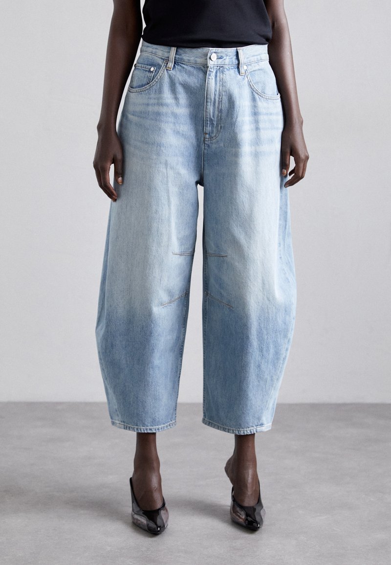 Ανοιχτό μπλε τζιν παντελόνι με φαρδιά εφαρμογή και ψηλή μέση, διαθέτοντας μπροστινές τσέπες, λεπτή φθορά και γυρισμένα τελειώματα. Υφασμάτινη υφή με λεπτομέρειες ραψίματος.