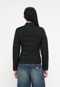 Mustast pehmendusega jope struktureeritud kraega, millel on tekstuuriga kangas ja horisontaalne õmblus. Üldse sobitatud helesiniste laiade säärtega teksadega.