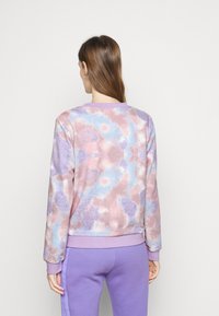 Felpa in pile dai colori pastello con un motivo tie-dye nei toni di rosa, blu e viola. Polsini e scollatura a coste.