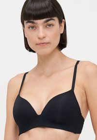 Black, seamless bra with a plunging neckline, thin adjustable straps, and a smooth fabric texture. No visible hardware or patterns.