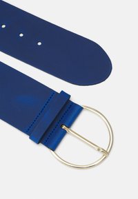 Blauwe leren riem met een gladde textuur, voorzien van een goudkleurige ronde gesp en meerdere verstelgaten, ontworpen voor een aanpasbare pasvorm.