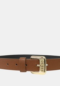 Cintura sintetica marrone con finitura texturizzata e fibbia in metallo dorato embossata con il nome del marchio. Presenta diversi fori di regolazione.