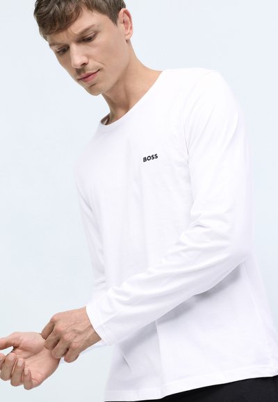 T-shirt blanc à manches longues avec un col rond et le logo noir "BOSS" sur la poitrine gauche. Fabriqué en tissu léger et lisse.