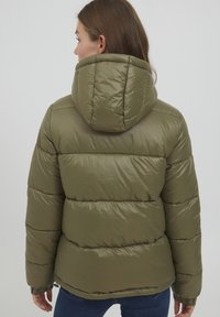 Giubbotto imbottito verde oliva con cappuccio, caratterizzato da sezioni trapuntate e una texture liscia e lucida. Chiusura con zip e polsini elasticizzati.