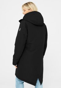 Černý izolační parka s velkou kapucí, logem na rukávu a mírně prodlouženým zadním lemem. Texturovaná tkanina s hladkým povrchem.