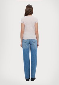 T-shirt rosa chiaro a maniche corte abbinato a jeans blu in denim larghi, caratterizzati da una vestibilità comoda e da un classico design a cinque tasche.