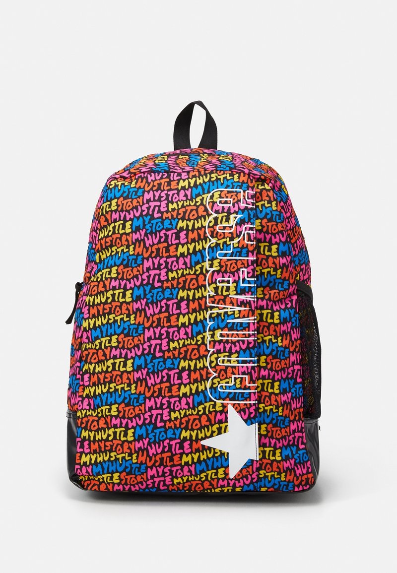 Sac à dos coloré couvert du texte répétitif "MY HUSTLE MY STORY" avec un logo vertical "CONVERSE" et une étoile blanche en bas.