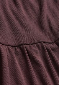 Close-up of dark purple ribbed fabric with gathered stitching creating a textured, wavy pattern on the surface.