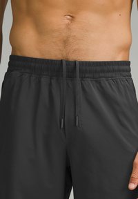 Svarta sportshorts med elastisk midja och dragsko. Slät textur, sidofickor och lös passform för komfort.