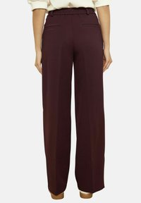 Bordo platām bikšu bikses ar elastīgu jostasvietu, sānu kabatām un gludu, teksturētu audumu ērtai valkāšanai.