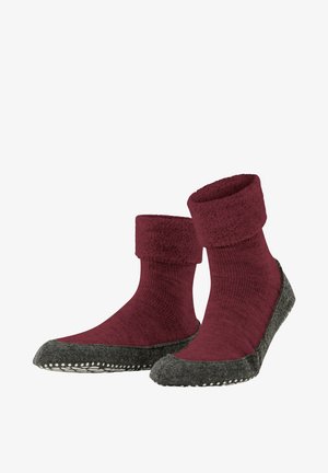 Rode gebreide sokken met een zachte, omgeslagen boord; grijze gestructureerde zool met witte stiksels langs de rand voor extra grip en duurzaamheid.