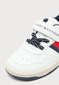 Λευκό sneaker Tommy Hilfiger με λεπτομέρειες σε ναυτικό μπλε και κόκκινο, μπλε κορδόνια και λευκό λουράκι με λογότυπο Velcro.