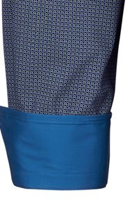Polsino a quadri bianchi e blu con orlo arrotolato blu scuro. Tessuto di cotone con una consistenza liscia e un motivo geometrico.
