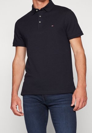 Polo en coton de couleur marine avec col, manches courtes, patte de boutonnage à trois boutons et un petit logo de marque près de la poitrine.