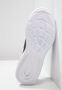 Zapatilla Nike con una suela de goma blanca con patrones texturizados, parte superior de color negro y un diseño elegante y moderno.
