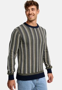 Pull en tricot rayé marine et beige avec des poignets et un ourlet côtelés. Présente un motif texturé et un col rond en marine contrasté.