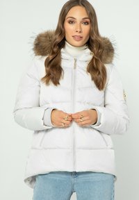 Bílá péřová bunda s kapucí s kožešinovým lemem, předním zipem a elastickými manžetami; má mírně delší zadní lem a postranní kapsy.