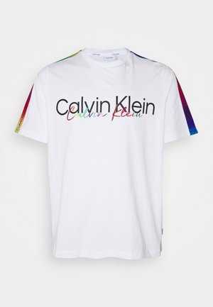 Chemise blanche à manches courtes avec logo "Calvin Klein" noir et multicolore sur la poitrine, et détails rayés arc-en-ciel sur les deux manches.