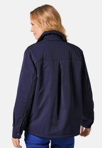 Dunkelblaue Jacke mit hohem Kragen, langen Ärmeln und gefaltetem Rückendesign. Hergestellt aus einem glatten, strapazierfähigen Stoff mit geknöpften Ärmelbündchen.