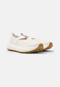 Vita slip-on skor av slät läder, med elastiska remmar och en texturerad tan gummi sula med rundade grepp.