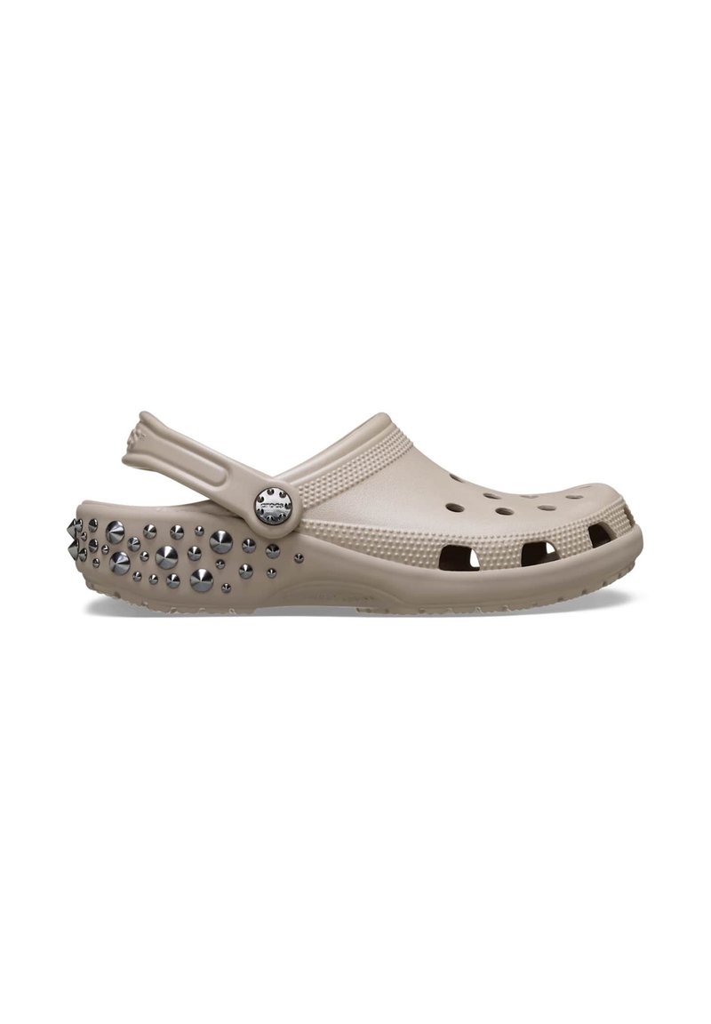 Beige Clog aus leichtem Material mit runder Form. Verfügt über Belüftungsöffnungen, einen Riemen und metallische Nieten auf der Außensohle.