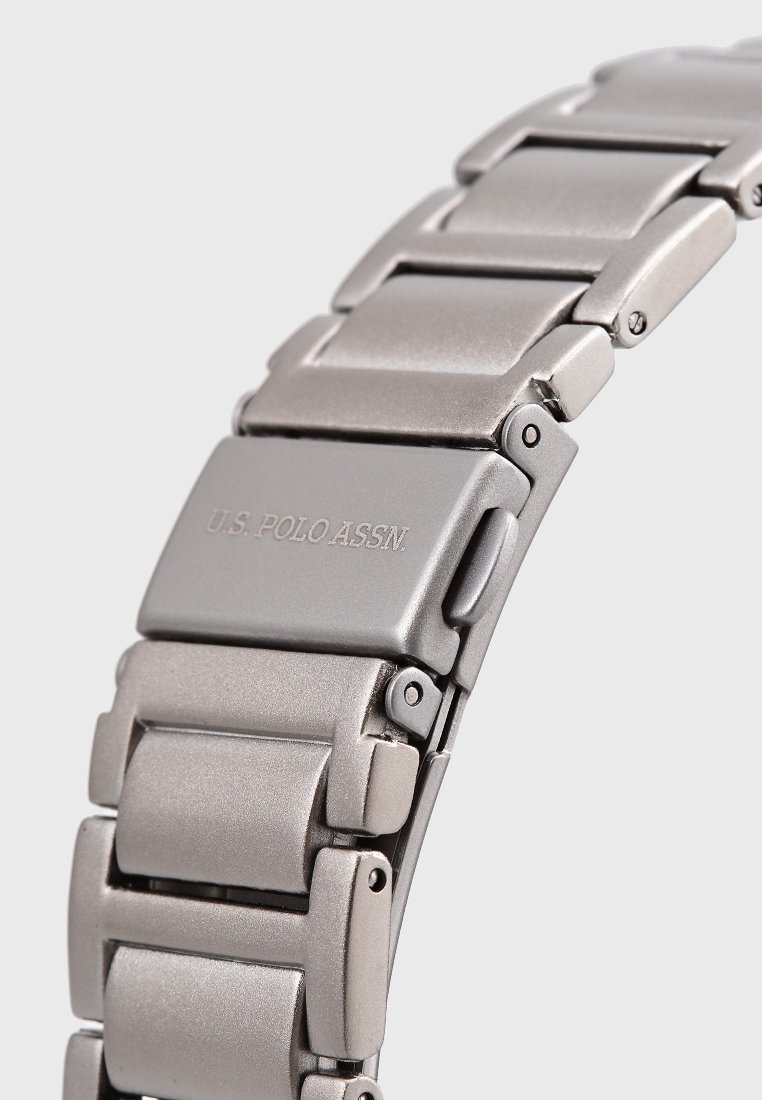Edelstahl-Armbanduhrband mit matter Oberfläche, ausgestattet mit ineinandergreifenden Gliedern und eingraviertem Logo. Silber-graue Farbe und glatte Textur.