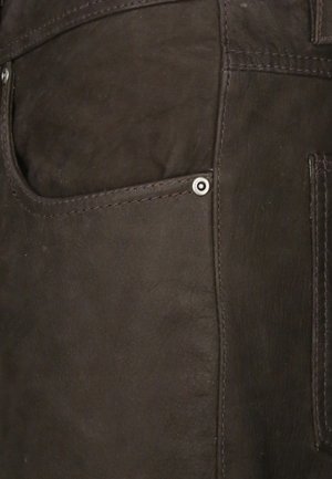 Donkerbruine leren broek met een gladde textuur, voorzien van een zijzak, zichtbare stiksels en een metalen drukknoopdetail bij de zak.