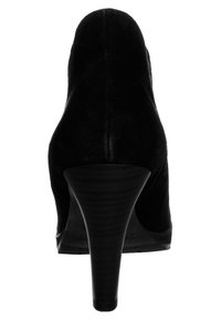 Zapato de tacón alto de ante negro con un diseño elegante, punta puntiaguda y un tacón texturizado que imita la madera. La vista trasera resalta una silueta suave.