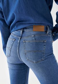Vaqueros de mezclilla azul oscuro con una etiqueta de cuero de Salsa Jeans, con un diseño ajustado, cinco bolsillos y costuras visibles.