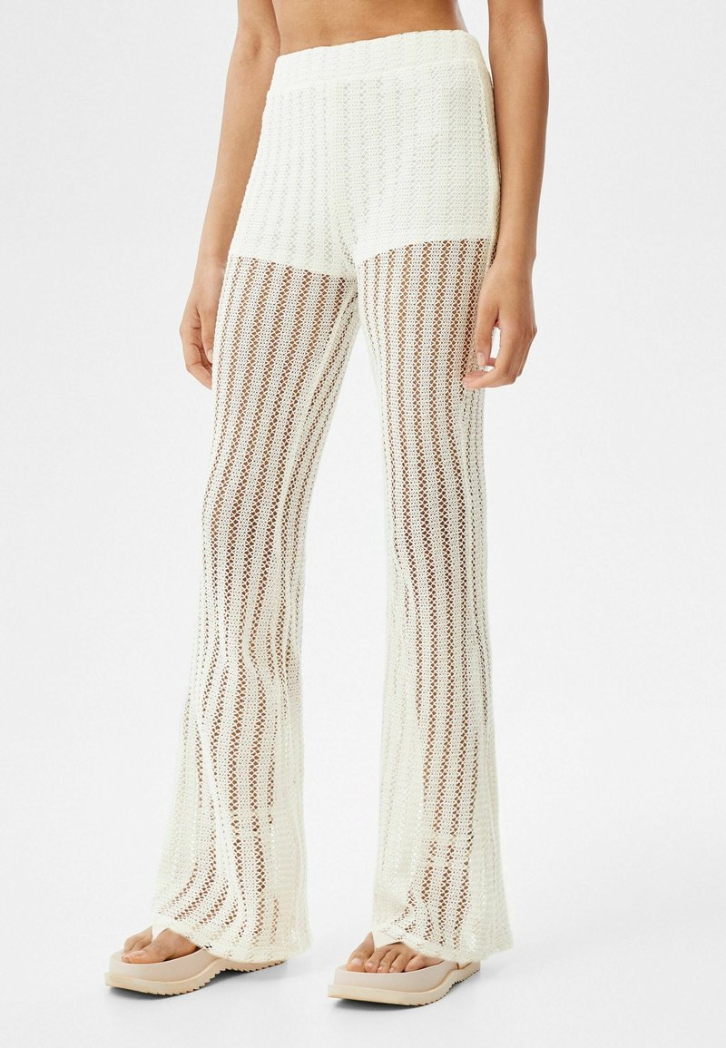Szydełkowane, rozkloszowane spodnie w kolorze ecru z teksturowanym wzorem. Oferują szeroki pas i otwarty, przewiewny fason.