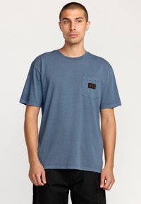 Blå bomulds T-shirt med korte ærmer, rund halsudskæring og en venstre brystlomme med et rektangulært patch-logo. Glat tekstur.