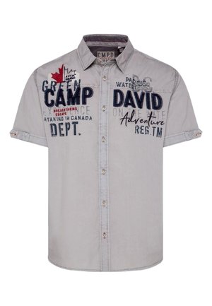 Kurzärmliges, hellgraues Hemd mit Knopfleiste, verziert mit verschiedenen gestickten Patches, darunter ein Ahornblatt und Textdetails, im lässigen Schnitt.