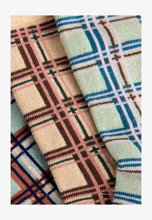 Tessuti lavorati a maglia con un mix di motivi a scacchi in tonalità pastello di rosa, marrone, verde e blu, con accenti di filo metallico.