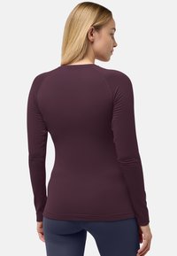 Maglione lungo a maniche con tessuto testurizzato e design aderente, caratterizzato da maniche raglan e scollatura rotonda. Superficie liscia con righe sottili.