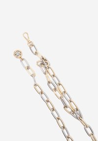 Guld- og sølvmetal kæde med forlængede led. Har en clasps og et rundt logo i den ene ende. Glat tekstur, moderne design.